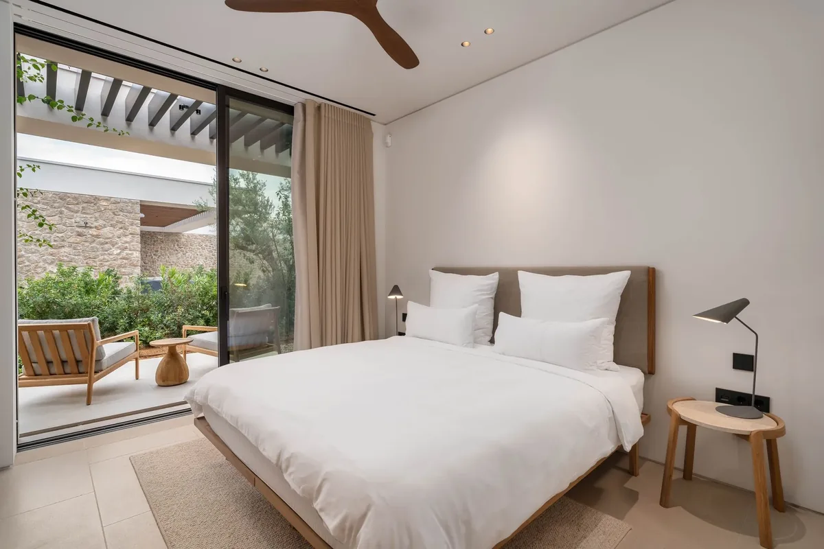 Bedroom with a double bed, natural materials and a door to the terrace