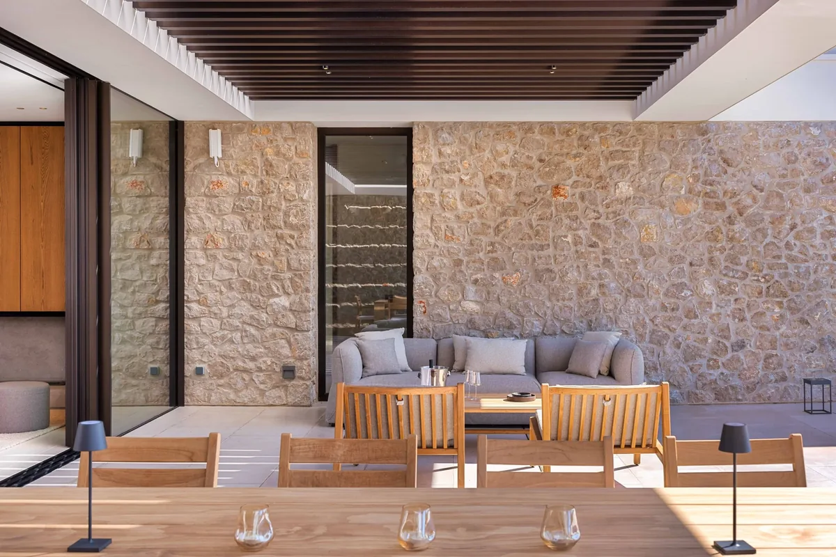 Covered outdoor seating and dining area with a stone wall