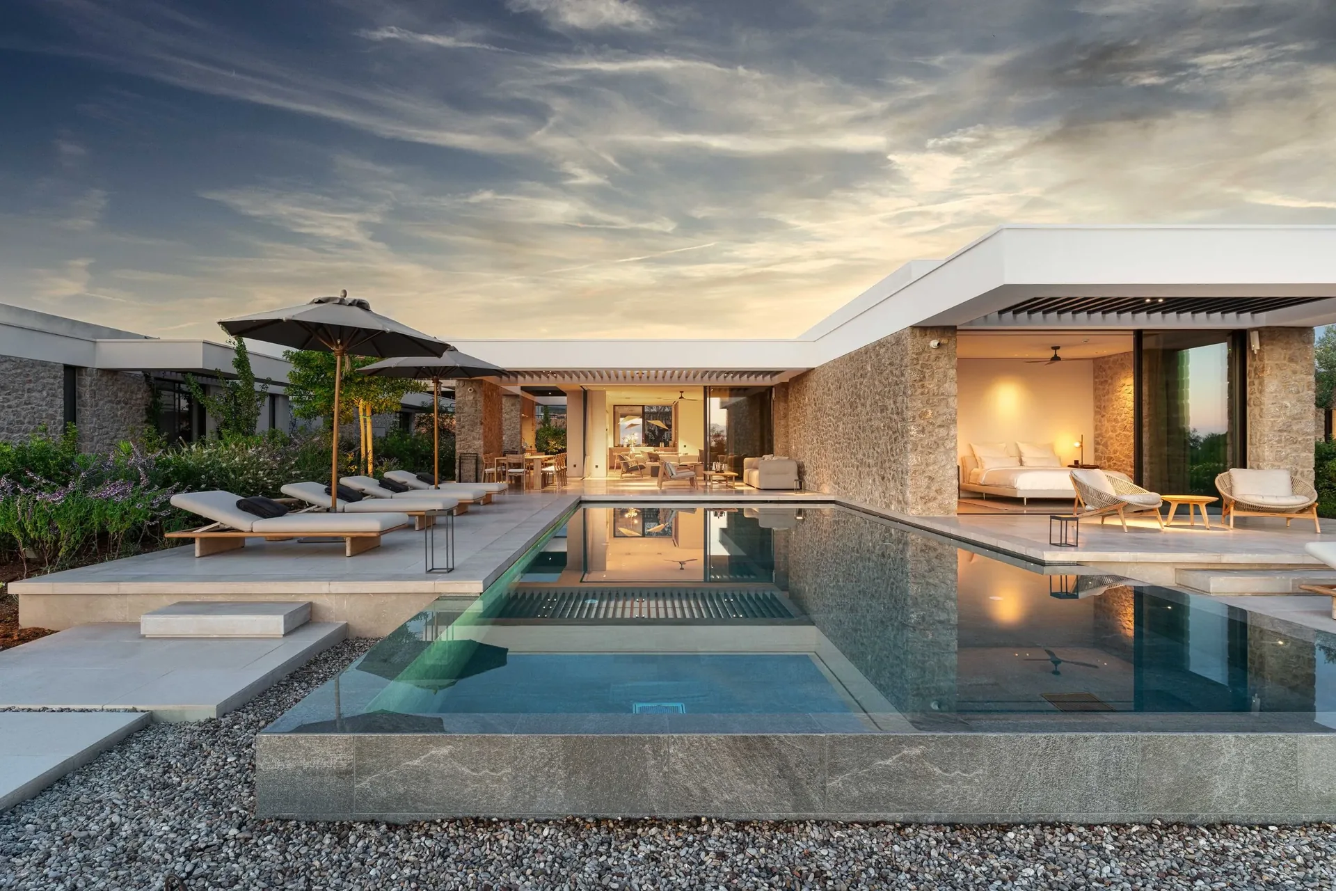 The private pool and illuminated stone villa at NiMax Residence at dusk