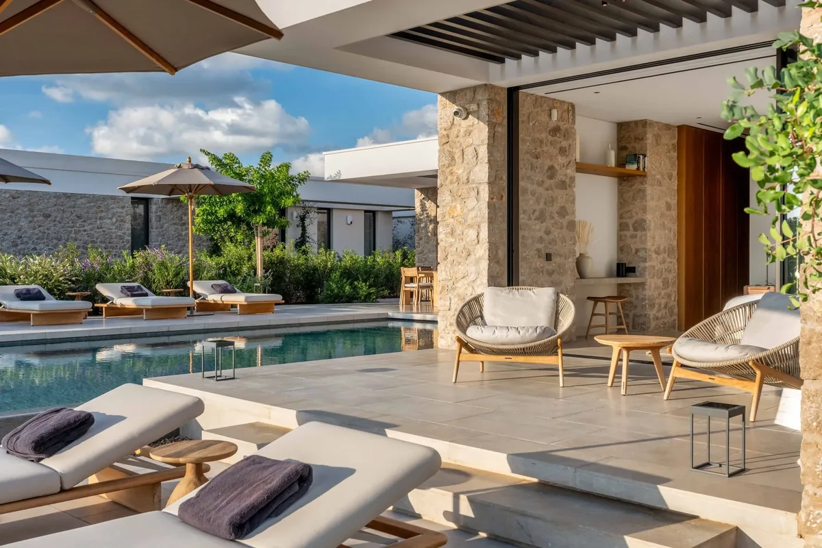 Sun loungers beside the pool, with a shaded stone terrace beyond